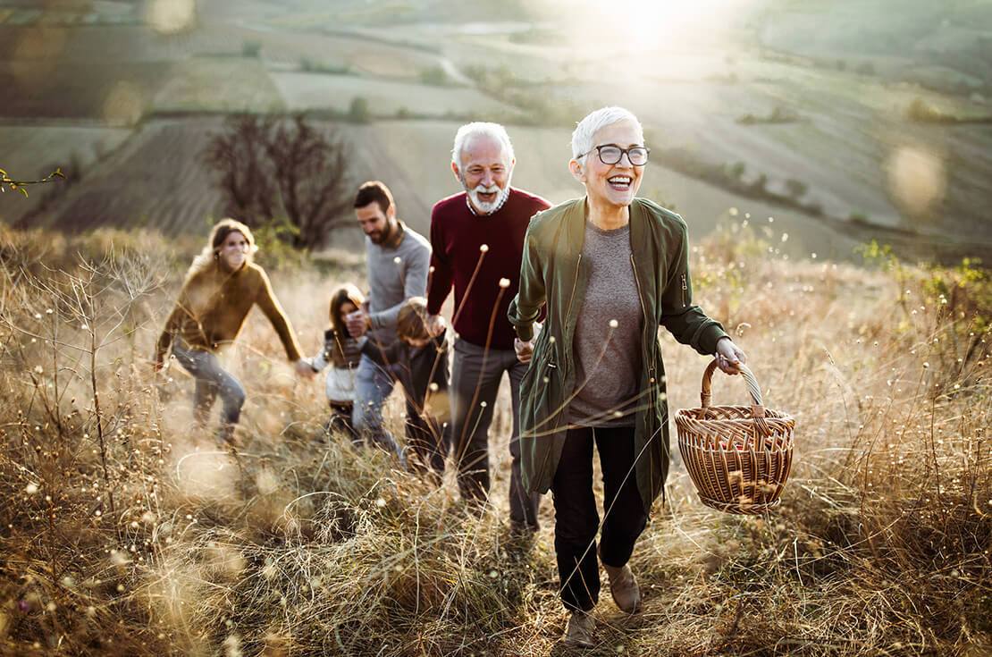 Happy senior woman leading her family to perfect picnic place on the hill